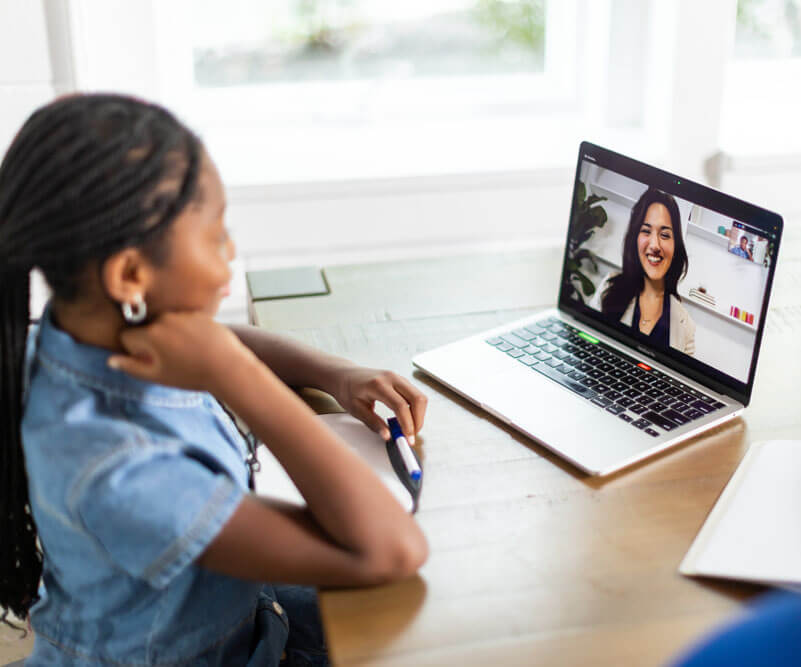 girl looking at the computer while an educational therapist is on the screen