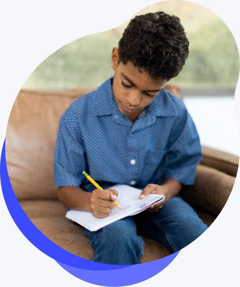 Child sits on couch and writes in a notebook